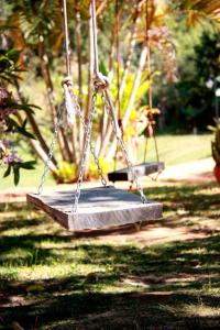 dois baloiços num parque com relva e árvores em Quinta da Bocaina em Amparo