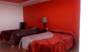 two beds in a room with red walls at Hotel Doña Crucita in Creel