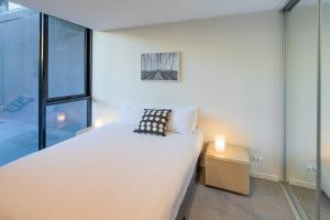 a bedroom with a large white bed and a night stand at Melbourne City Apartments - Teri in Melbourne