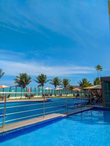 uma grande piscina com palmeiras e guarda-sóis em Tabatinga Flat - Beira Mar em Conde