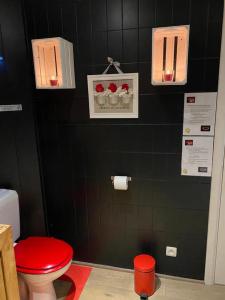 a bathroom with a red toilet and a black wall at La Milardière in Theux