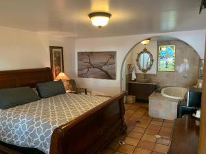 a bedroom with a bed and a tub and a sink at Chantico Inn in Ojai