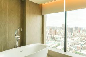 a bathroom with a tub and a large window at FX Hotel Tainan in Tainan