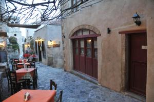 an outdoor patio with tables and chairs and two doors at Pietra Suite in Monemvasia