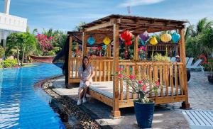 a woman sitting on a bench next to a pool at Fairy Hills Hotel in Mui Ne