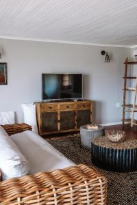 ein Wohnzimmer mit einem Sofa und einem Flachbild-TV in der Unterkunft Boplaas Guesthouse in Op-die-Berg