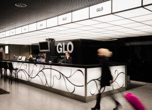 a person walking past a bar in a building at GLO Hotel Airport in Vantaa