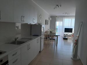 a kitchen with white cabinets and a dining room at Valentino apartments Bouganville Bay Saranda in Sarandë