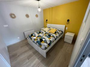 1 dormitorio con cama y pared amarilla en Logements équipés à Onnaing avec espace Balneo en OPTION proche Toyota, autoroute et Valenciennes en Onnaing