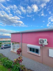 ein rosafarbenes Gebäude mit einem Auto auf einem Parkplatz in der Unterkunft Le Tuit-Tuit **** in Sainte-Suzanne