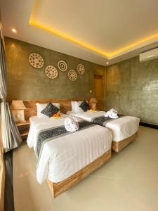 a bedroom with two beds with white sheets at Goutama Homestay in Ubud