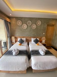 two beds in a hotel room with stuffed animals on them at Goutama Homestay in Ubud