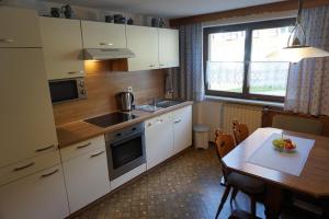uma cozinha com armários brancos, uma mesa e uma janela em Gästehaus Metzler em Bizau