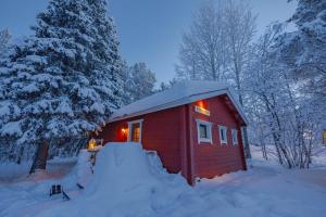 una piccola cabina rossa nella neve di notte di Ylläksen Yöpuu ad Äkäslompolo