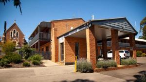 a brick building with a parking lot in front of it at Bega Downs Motor Inn in Bega