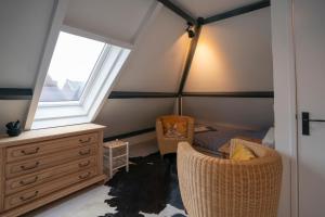 een zolderkamer met 2 stoelen, een dressoir en een raam bij Bed & Breakfast Mir Lo in Mierlo