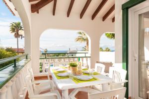 Una mesa blanca y sillas en un balcón con vista al mar. en Villa Carolina, en Son Bou