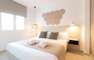 1 dormitorio con 1 cama blanca grande y 2 toallas en Calafell Home Apartments, en Calafell