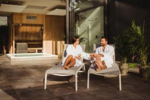 un homme et une femme assis sur des chaises avec un bébé dans l'établissement Golden Lakes Hotel, à Boussu-lez-Walcourt