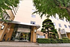 a building with a tree in front of it at Reisenkaku Hotel Ekimae in Fukuoka