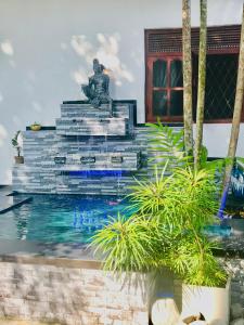 una fuente con una estatua delante de un edificio en Travellers Halt, en Ratnapura