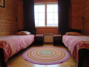 two beds in a room with a rug on the floor at Männi Farm Holiday House in Eoste