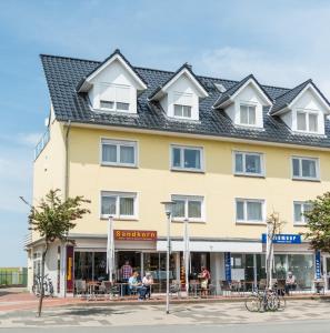 a large yellow building with people sitting outside of it at Landhaus Braband Ferienwohnungen - Cuxhavener Straße 96 in Cuxhaven