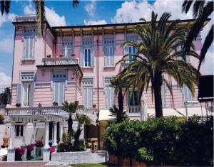 a pink building with palm trees in front of it at Hotel Europa in Lido di Camaiore