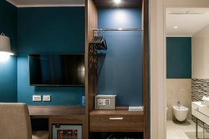 een badkamer met een televisie en een badkamer met een wastafel bij Fly Decó Hotel in Lido di Ostia