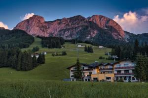 ein Haus auf einem Hügel mit Bergen im Hintergrund in der Unterkunft Gasthaus-Landhotel Traunstein in Abtenau
