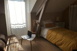 1 dormitorio con cama y mesa con ordenador portátil en Maison Chiche, en Bain-de-Bretagne