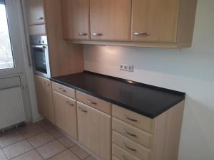 a kitchen with a black counter top and wooden cabinets at schöne 3 Zimmer Stadtwohnung in Eppelheim