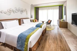 Holiday Inn Resort Sanya Bay, an IHG Hotel في سانيا: سريرين في غرفة الفندق مع تلفزيون