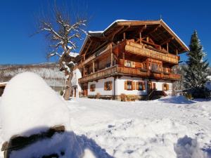 uma cabana de madeira na neve com um snowboard à frente em Haus Dirol em Kirchberg in Tirol