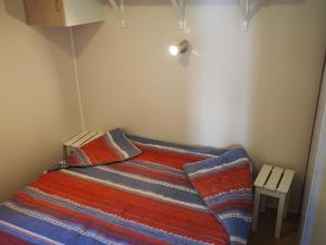 a small bedroom with a bed with a colorful blanket at LE CASQUE ROI in Salavas