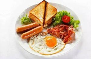 a plate of breakfast food with eggs sausage and toast at Hotel Rose Mansion Manyata Tech Park in Bangalore