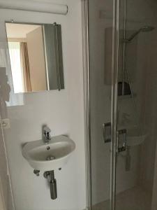 a bathroom with a sink and a shower with a mirror at Zeedijk Appartement in Knokke-Heist