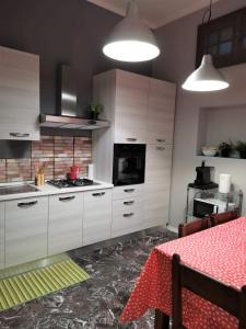 Una cocina con gabinetes blancos y una mesa con un mantel rojo. en Bnbook-Villa Molinari, en Milán
