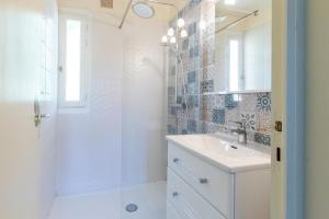 a white bathroom with a shower and a sink at Appartements L'Acacia - plage d'Argent à 300m in Coti-Chiavari