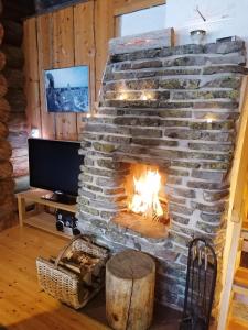 a stone fireplace in a living room with a television at Otsontupa Apartment in Ruka