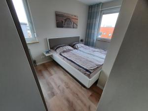 a small bedroom with a bed and two windows at Haus am Deich Wohnung 14 in Dahme