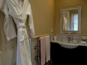 a bathroom with a sink and a white shower curtain at La Cabriere Country House in Franschhoek