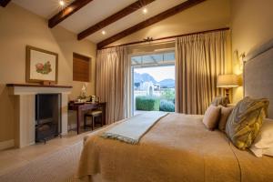a bedroom with a bed with a fireplace and a window at La Cabriere Country House in Franschhoek