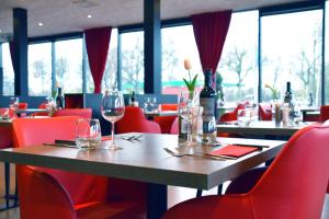 فندق باستيون روتردام زويد في روتردام: مطعم وكراسي حمراء وطاولة خشبية مع كؤوس للنبيذ