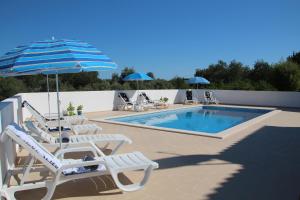 a swimming pool with chairs and an umbrella and a swimming pool at Villa Olive in Loulé