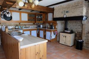 cocina con armarios de madera y encimera en Les Portes Vertes en Mairé-lʼEvescault