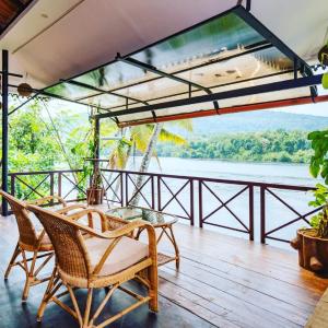 a balcony with chairs and a view of the water at Munkudil Ayurveda & Yoga Retreat in Kuttampuzha