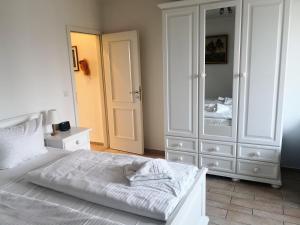 a bedroom with a white bed and a large mirror at Das Landhaus am Haff LHH B06 in Stolpe