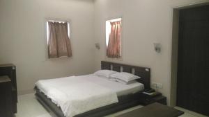 孟買的住宿－帕爾斯酒店，一间卧室配有一张带白色床单的床和两个窗户。