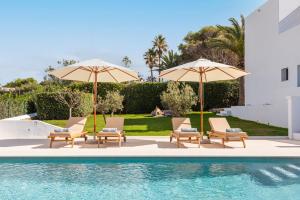 a group of chairs and umbrellas next to a pool at Villa Baixa - Es Canutells in Mahón